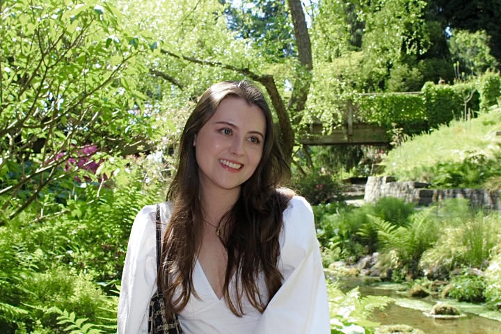 Girl smiling in a white blouse in front of a lush nature background